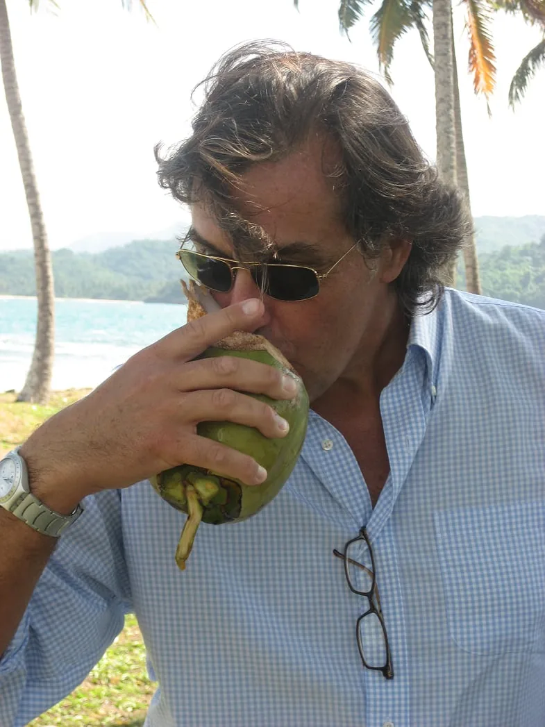 Baudilio Ruiz drinking from a coconut under the palms