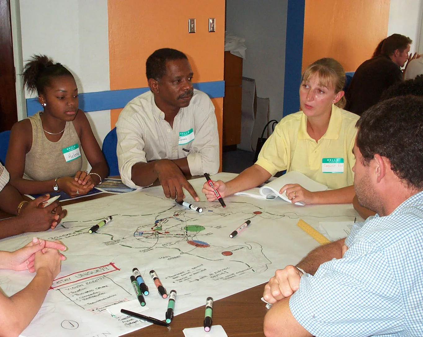 A workshop table in Road Town: residents with markers over a hand-drawn map of the town
