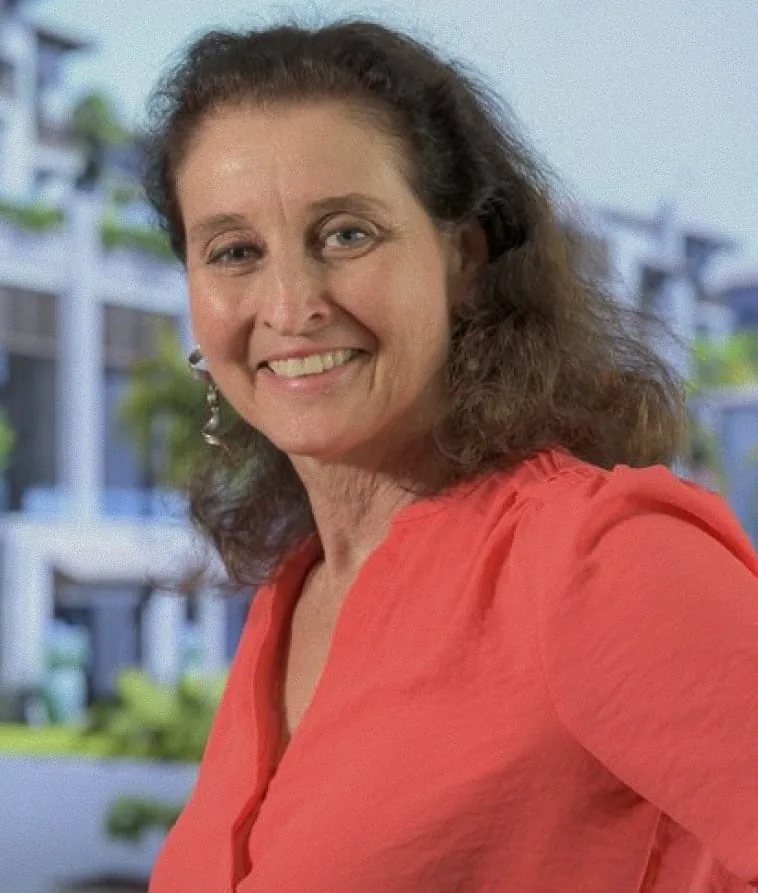 Liora Haymann in a red blouse, smiling, a rendering behind her
