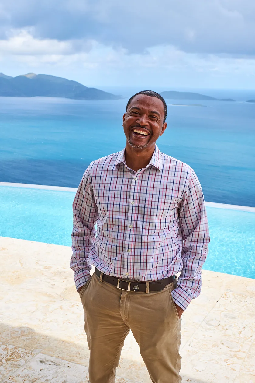 Marvin Flax laughing, standing by an infinity pool above the sea and the islands of the BVI