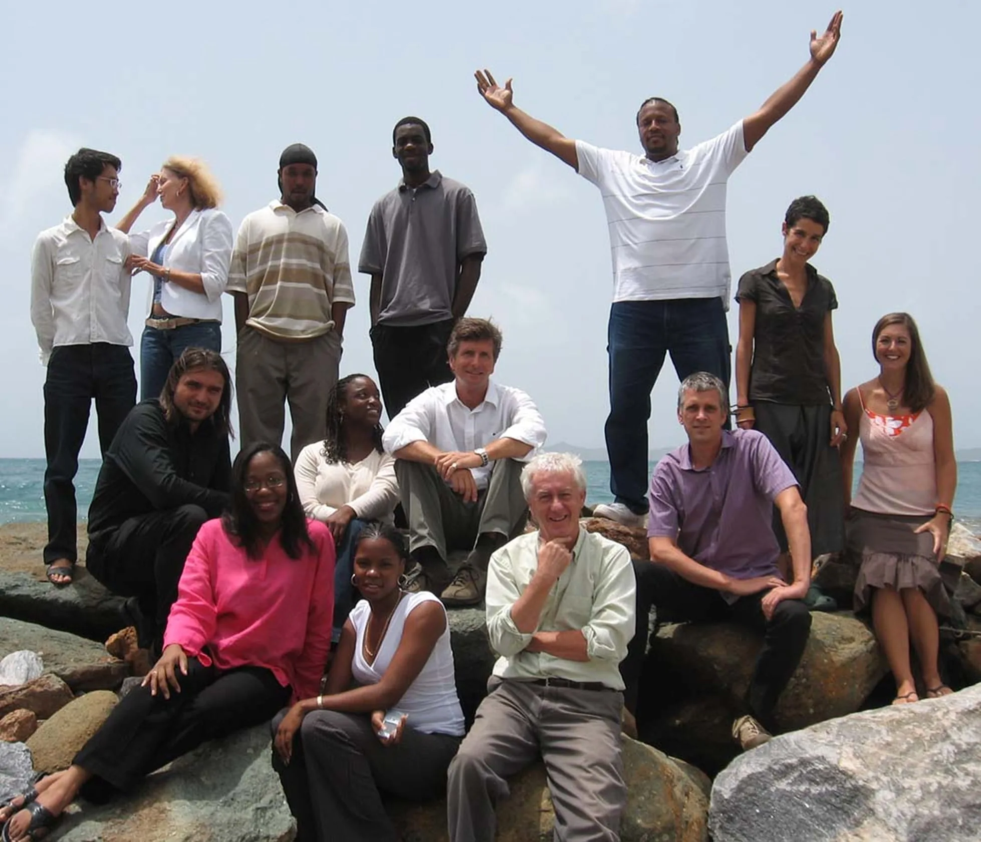 The OBMI Tortola team posed on the rocks by the sea, one man at the back with both arms raised