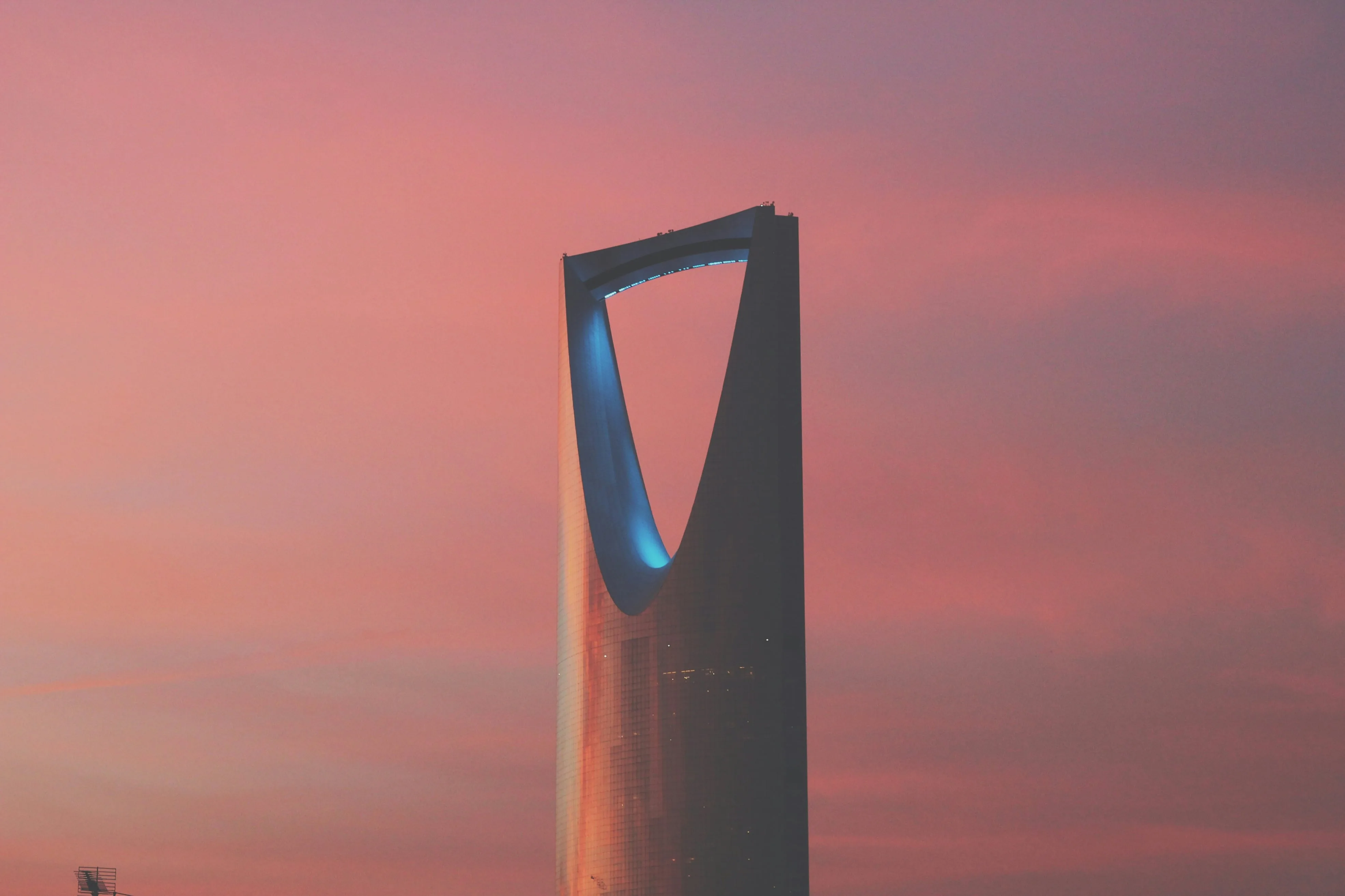 The Kingdom Centre tower in Riyadh against a pink evening sky