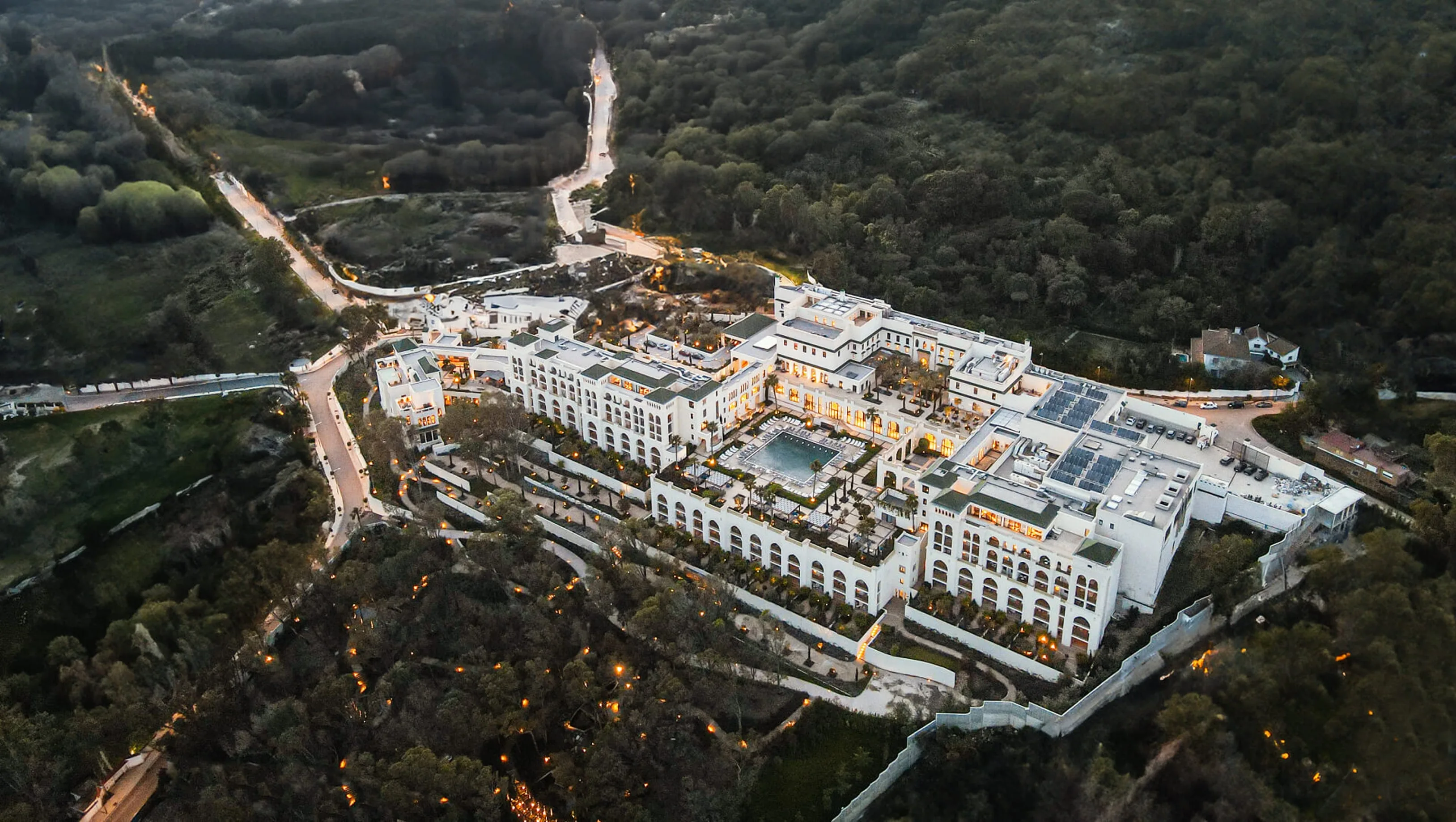 Fairmont Tazi Palace at dusk, seen from the air on its wooded hill above Tangier