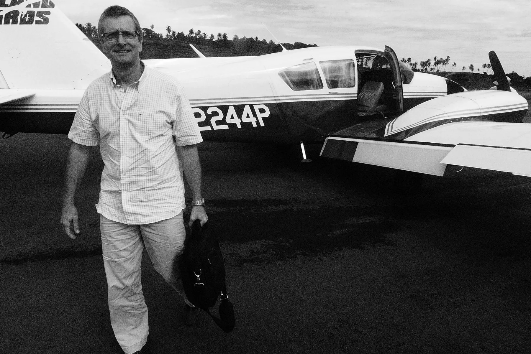 Tim Peck beside a twin-engine island plane on an airstrip