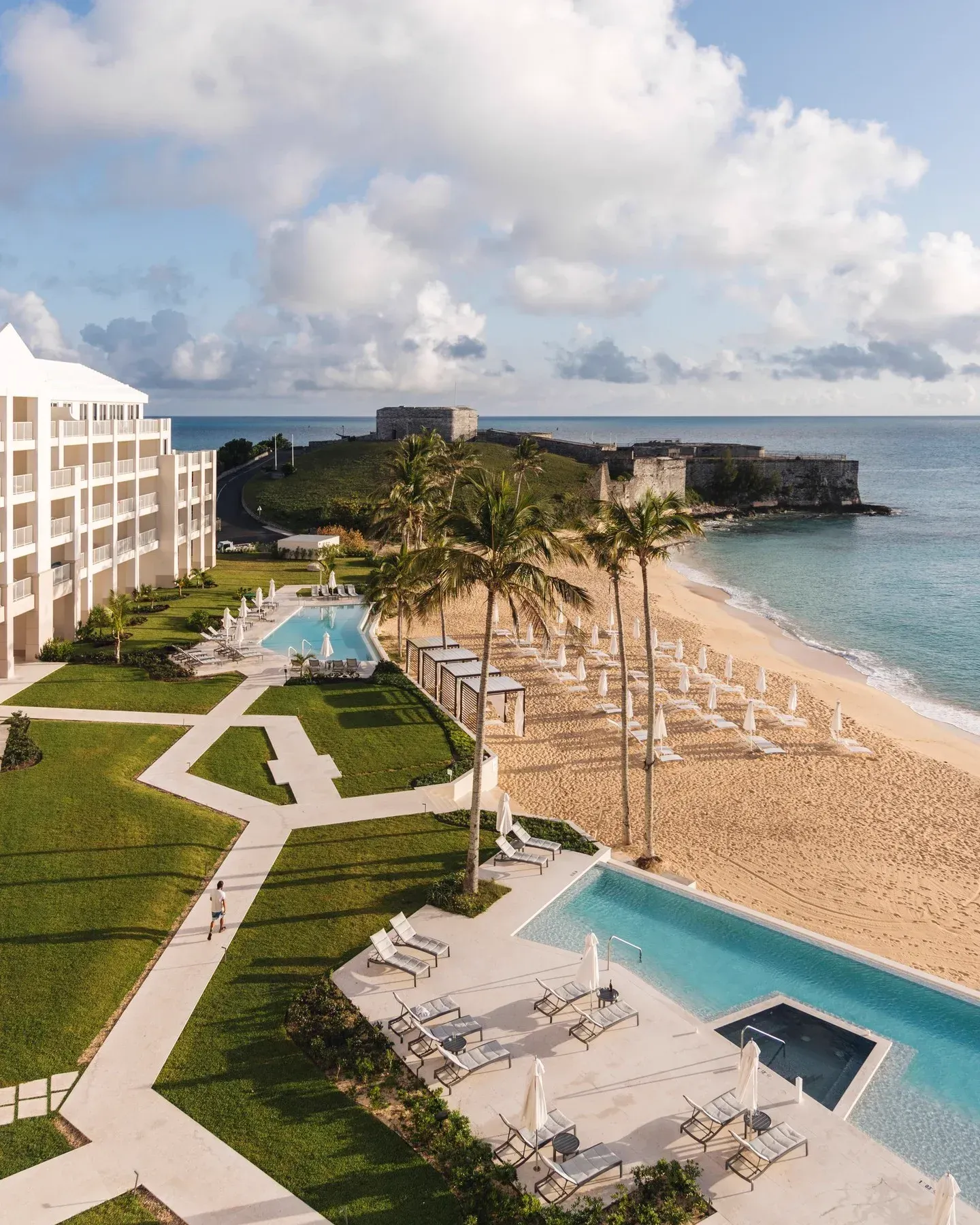 The pools and the beach from above, palms between them, the fort at the point