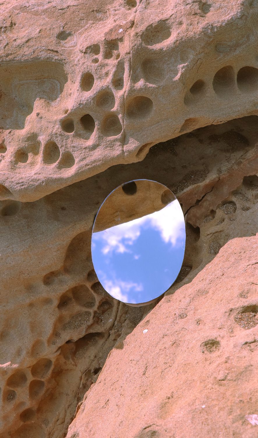 Mirror reflecting the sky on a rocky landscape