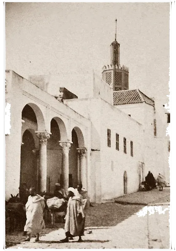 Sepia photograph of an arcade and a minaret in Tangier, figures in the street