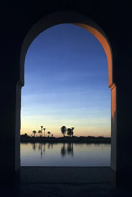 A lagoon at dusk through an arch, palms on the far shore