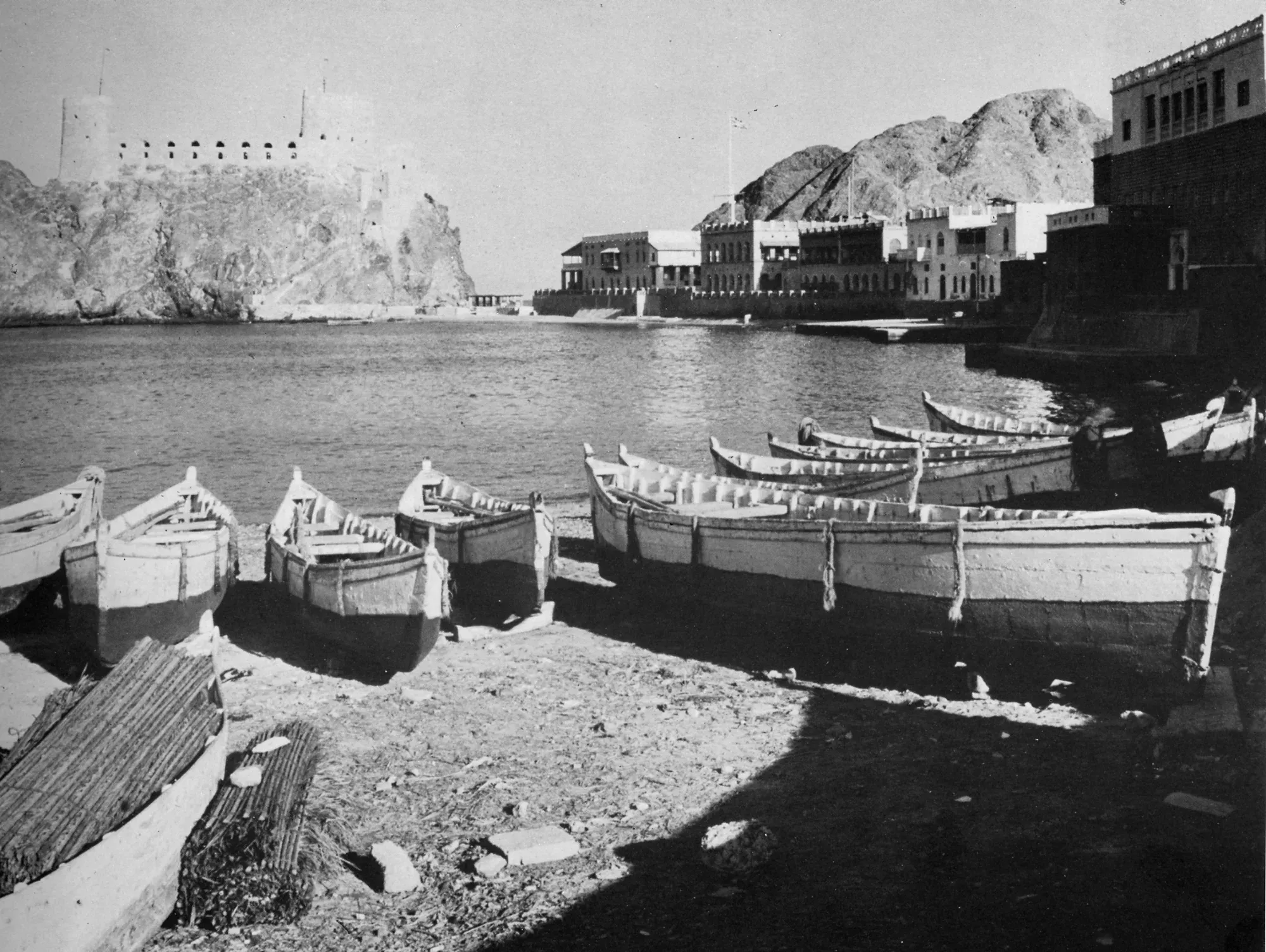 Fishing boats drawn up on the shore, a fort on the rock across the water