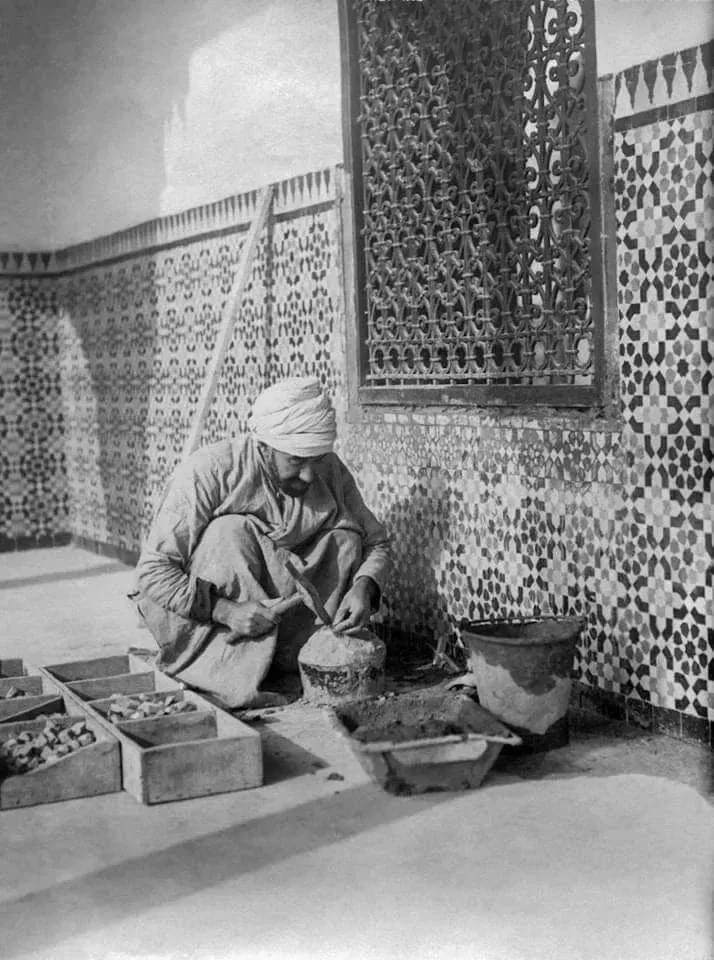 Archival photograph of a zellige artisan cutting tiles by hand