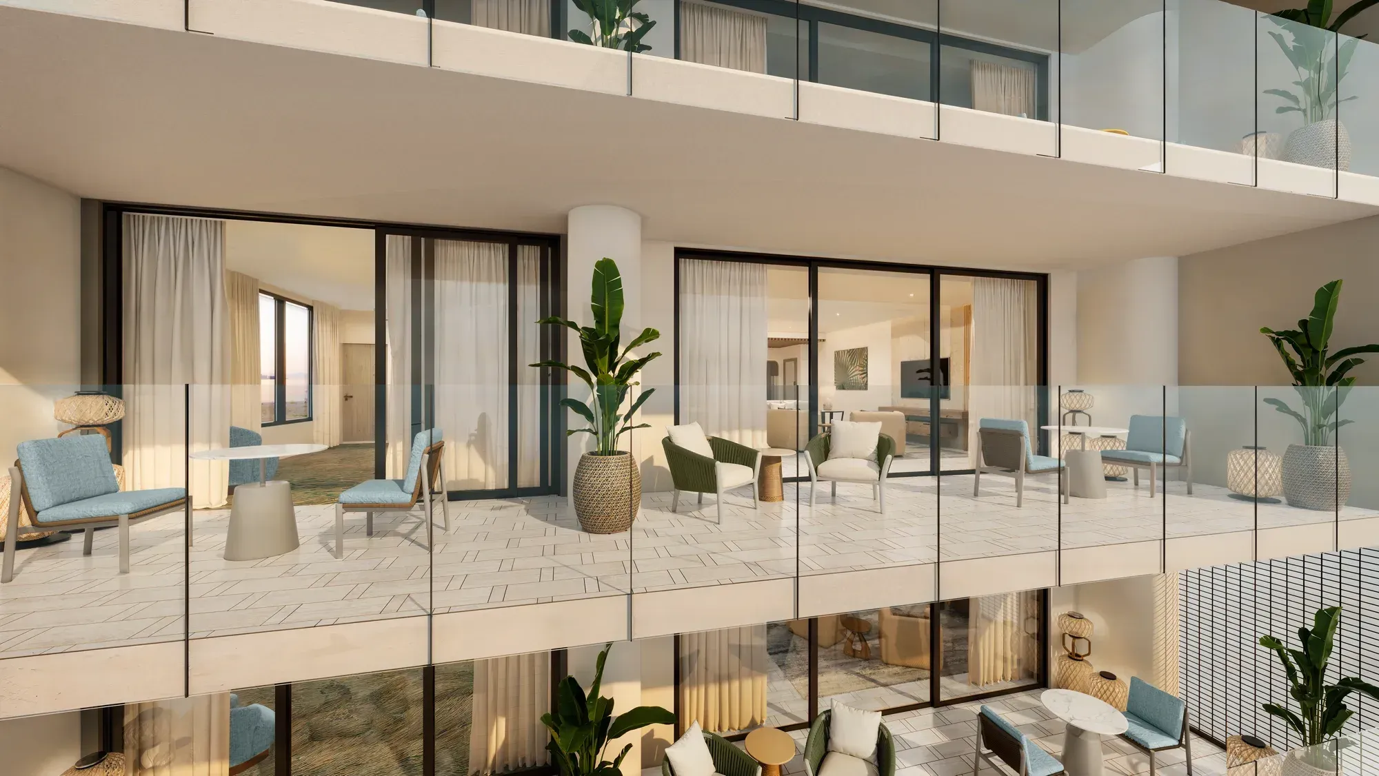 Two floors of glass-fronted balconies with chairs and planters, the rooms lit behind
