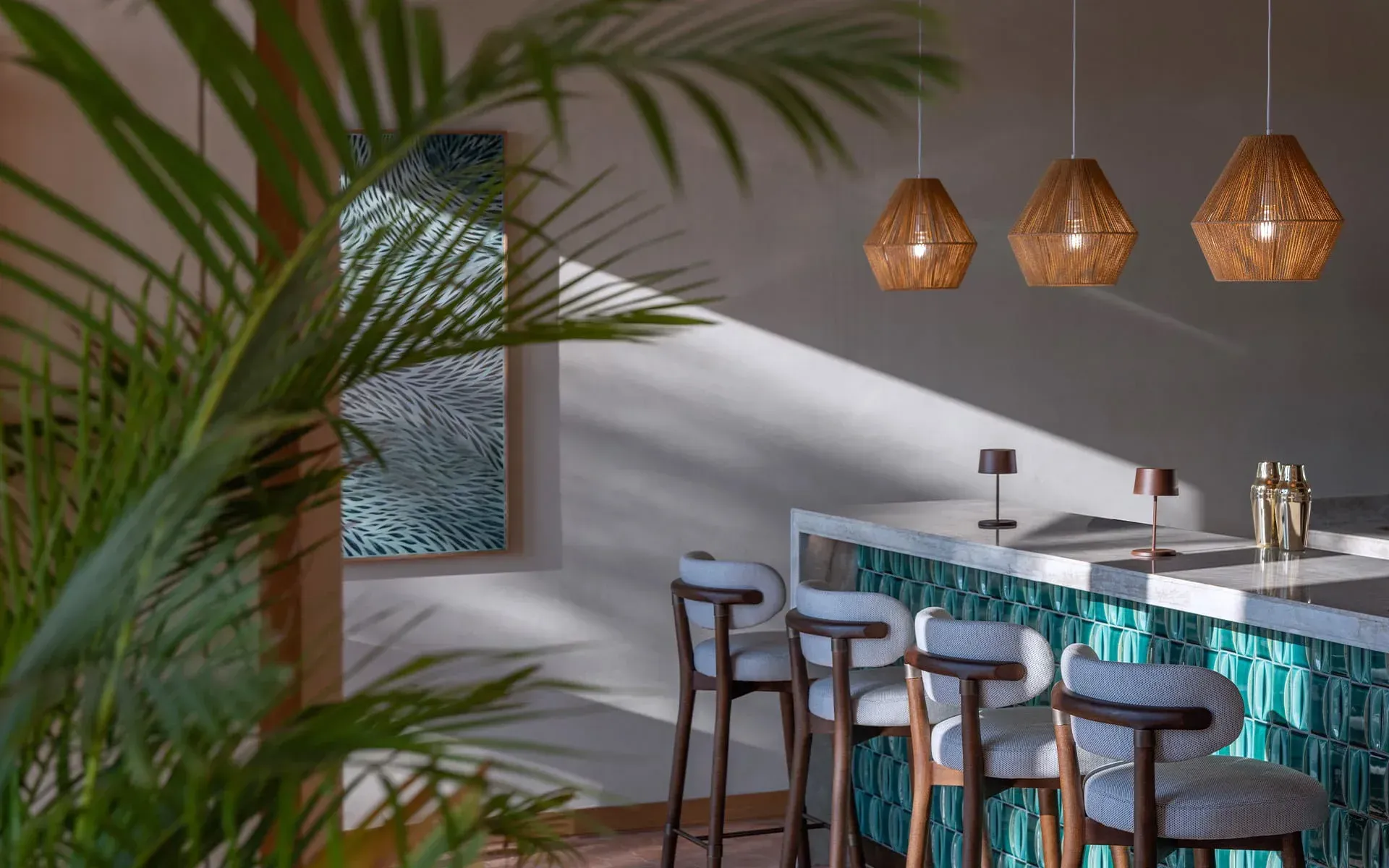 Rope pendants over the bar, late light on the plaster, a palm in the foreground