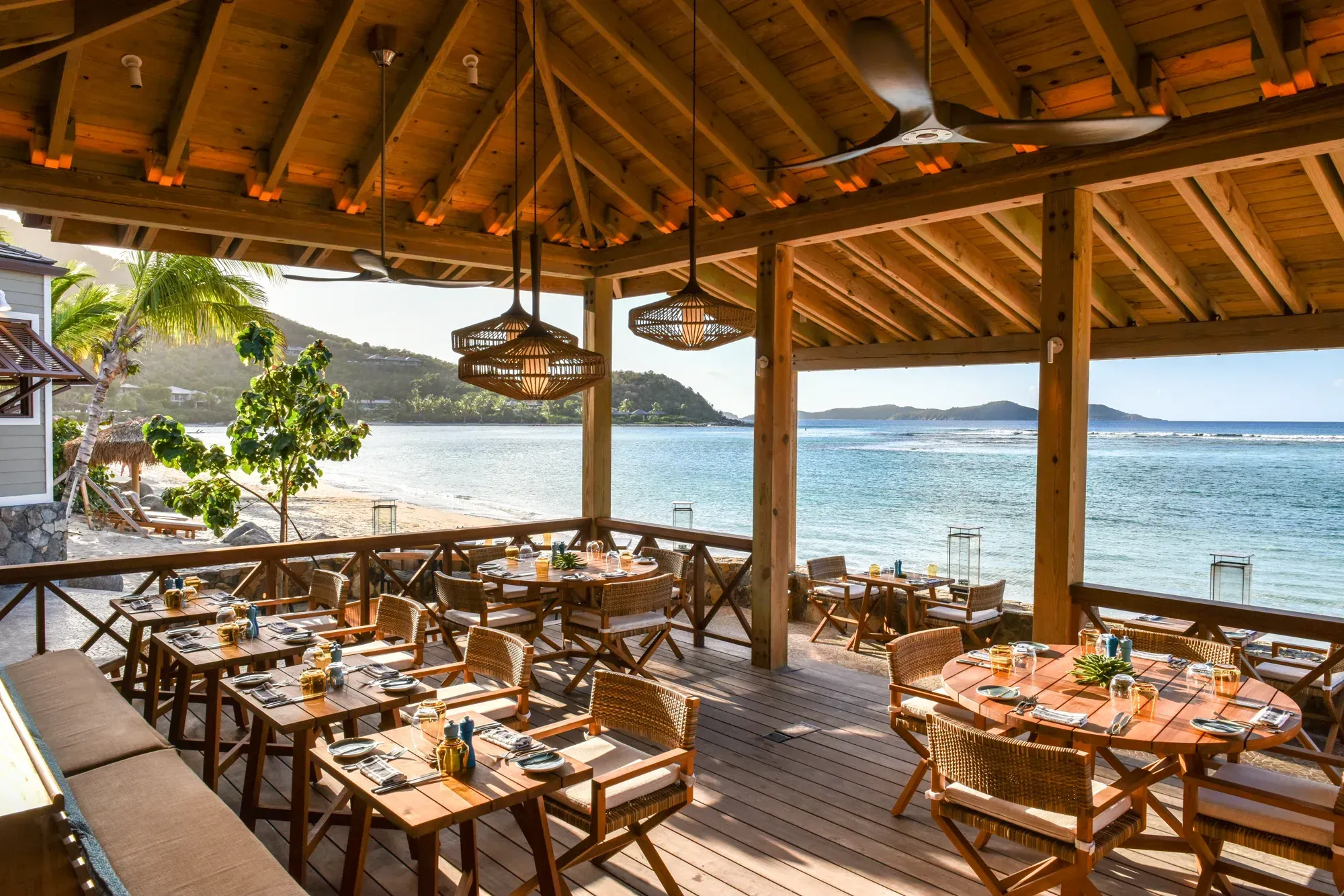The Beach Grill: a timber pavilion open to the beach, rattan pendants over the tables