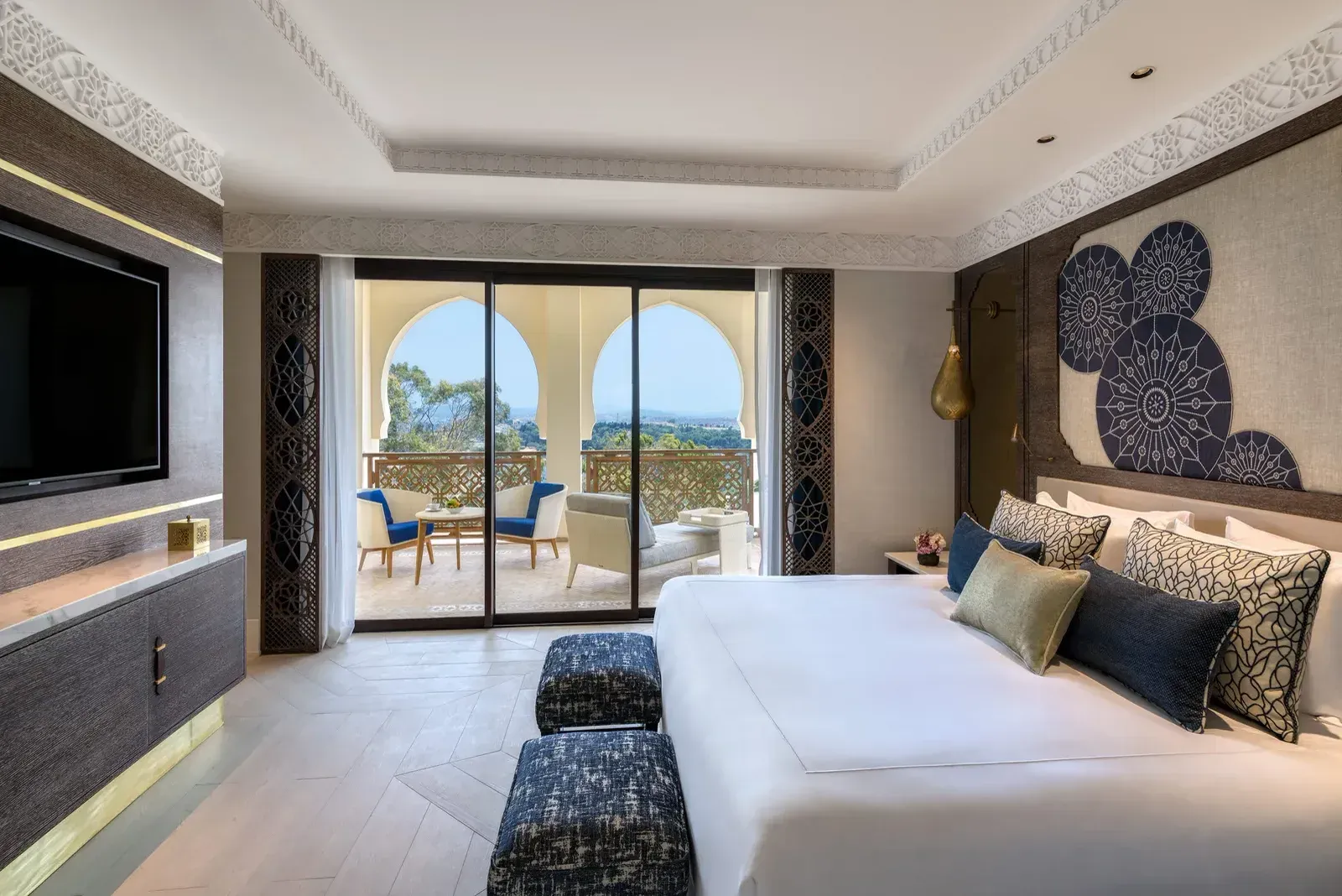 A guest room in blue and white, its terrace through pointed arches, the city beyond