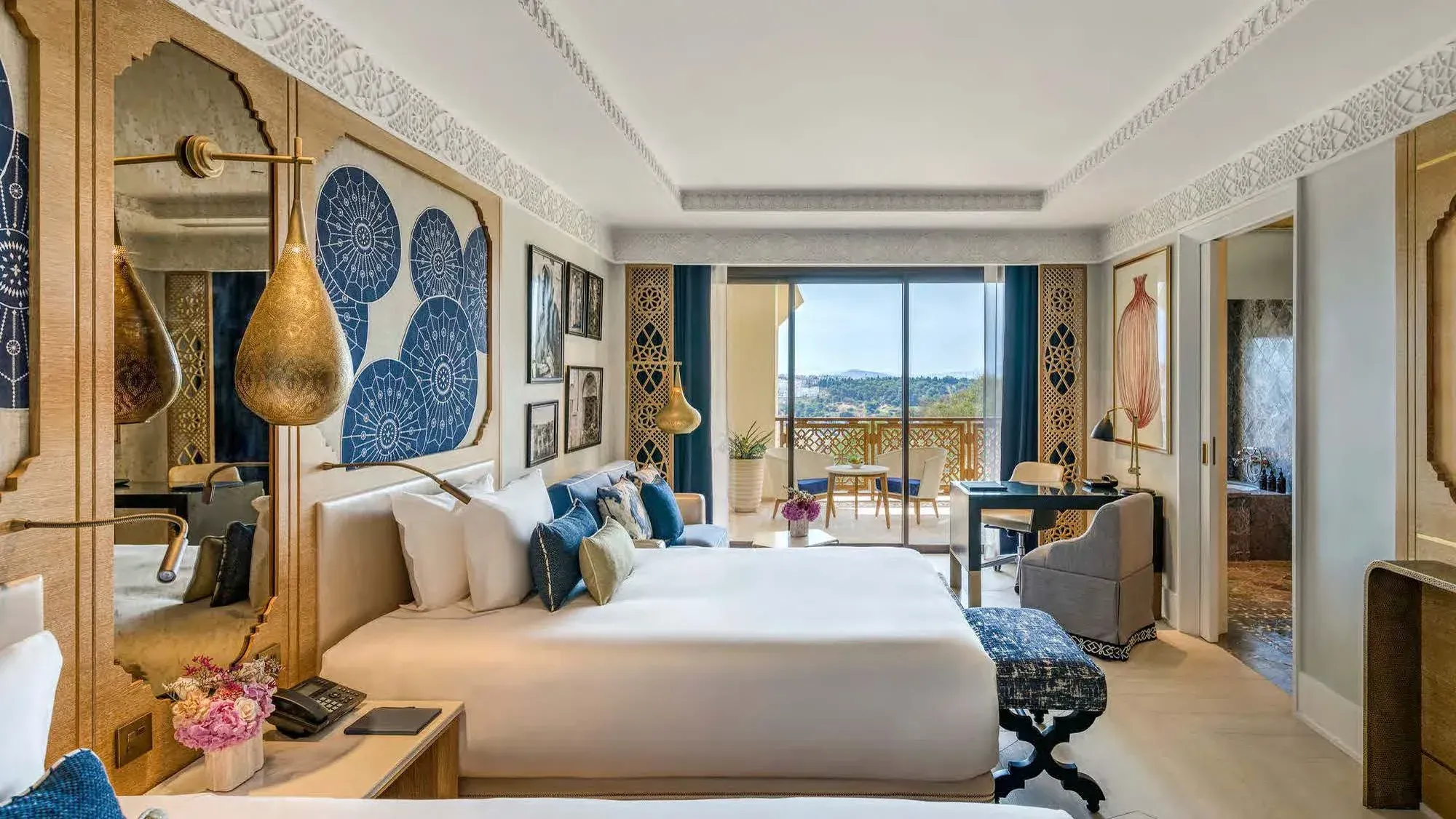 A guest room: brass lanterns, blue medallions over the bed, a balcony onto the city