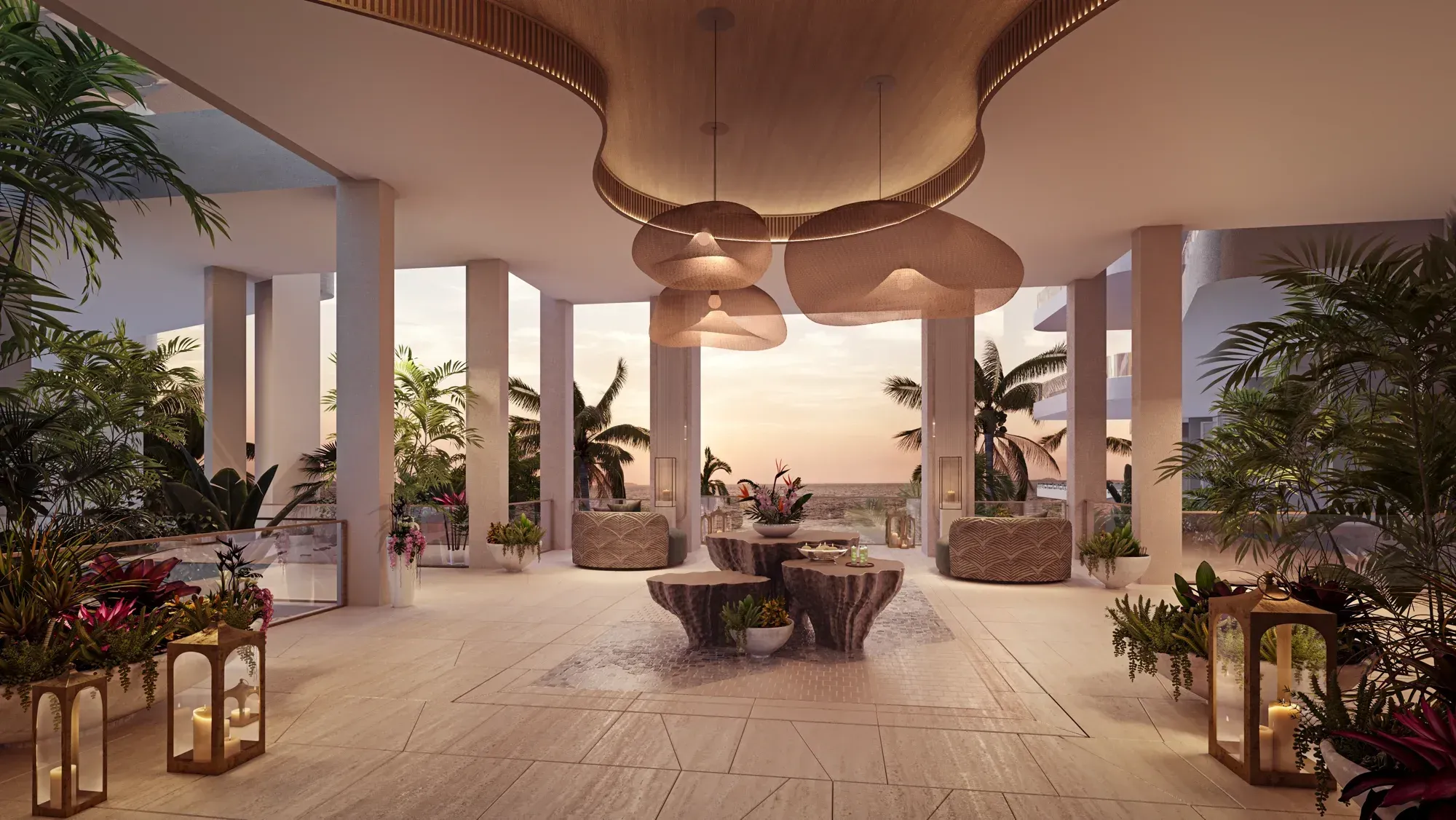 The lobby at dusk: rattan pendants over stone tables, palms and the sea through the columns