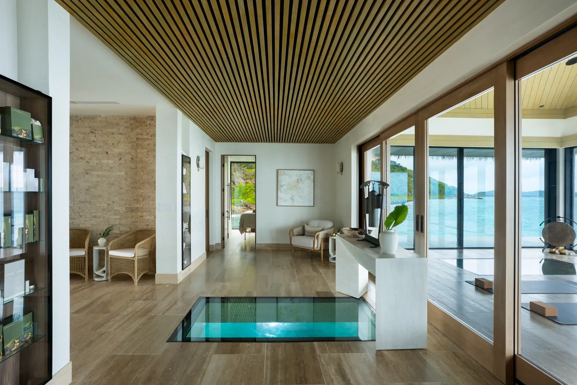 The lobby: a glass floor, wicker chairs against a stone wall, the studio beyond the doors