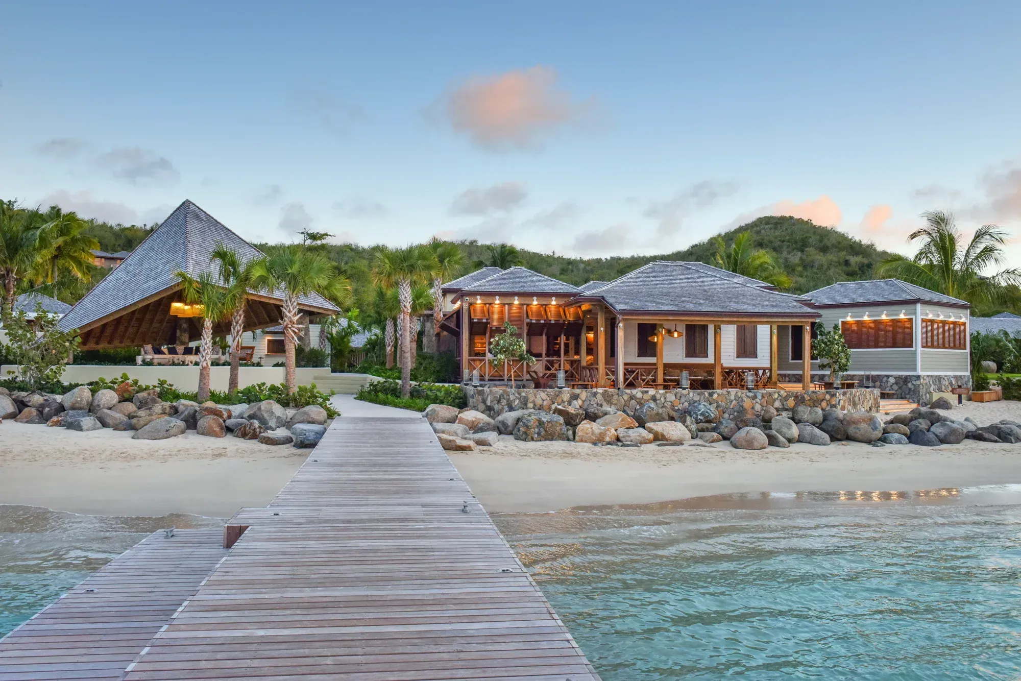The beach pavilions from the pier at dusk, stone, timber and shingle above a rock wall