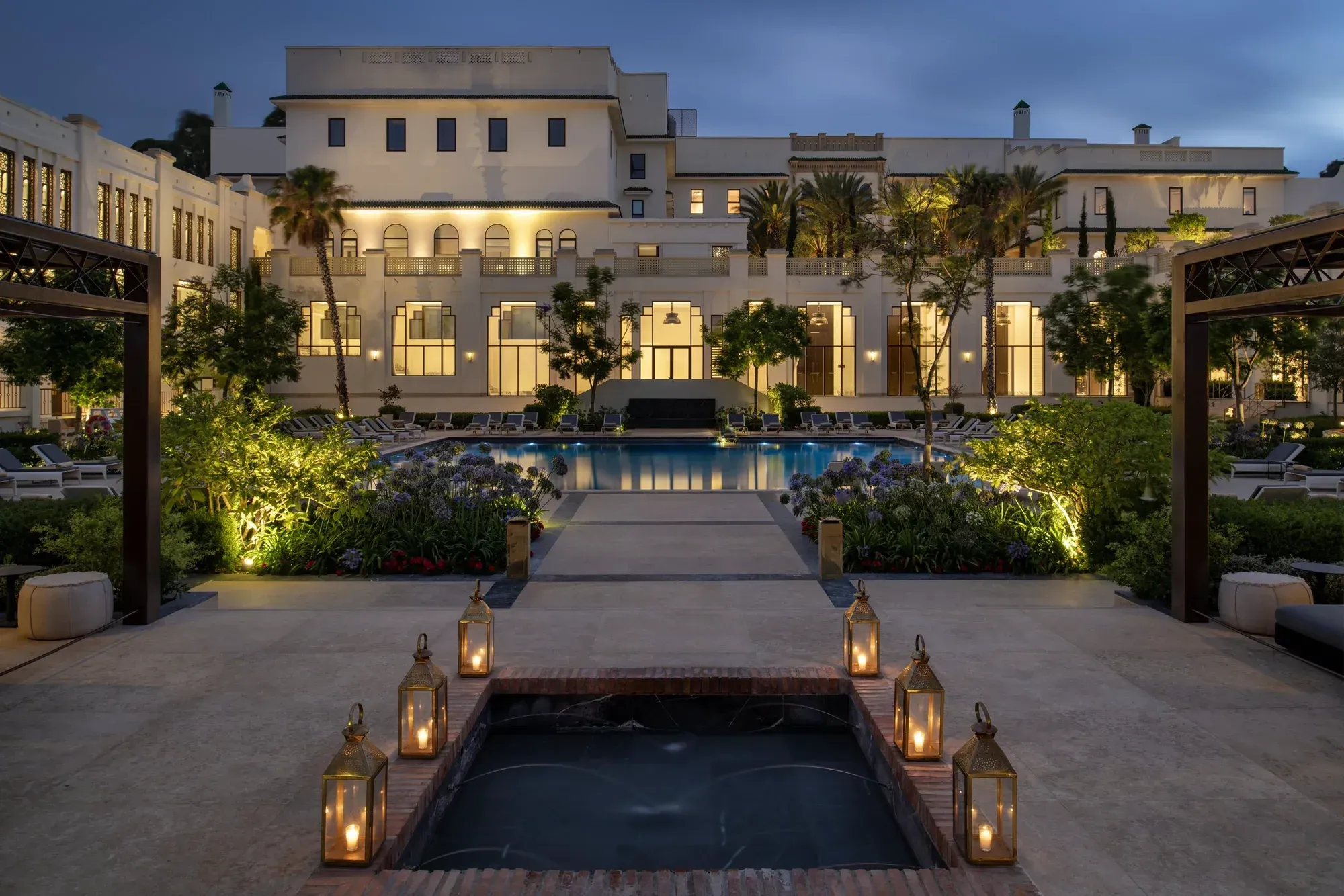 The palace facade lit at night across the pool, lanterns on the steps