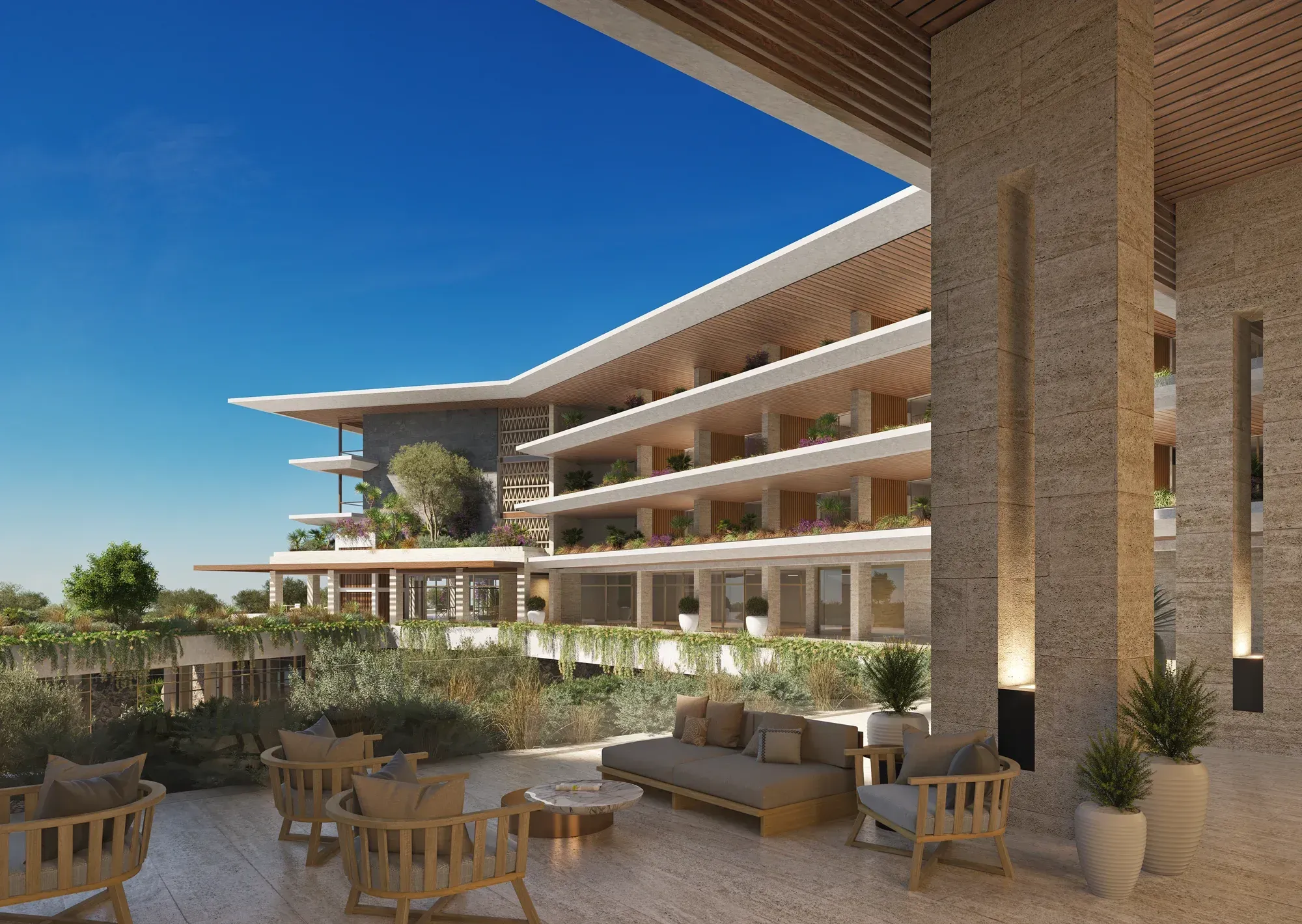 A stone terrace with cane armchairs, the stepped hotel wings and their planted balconies beyond